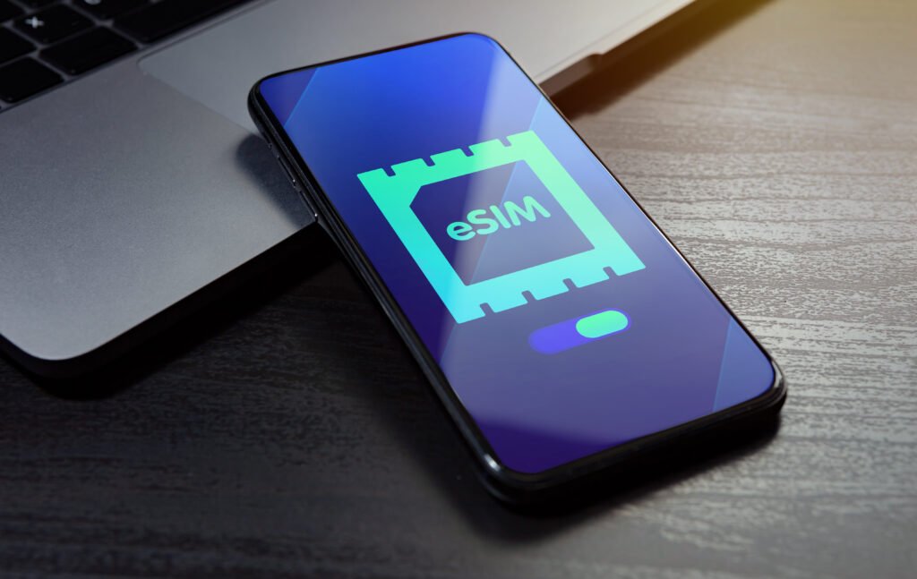 eSIM technology concept. Embedded SIM electronic phone sim card - mobile cellular global internet communication technology. Close up smartphone lying on a wooden table with an esim icon on the screen
